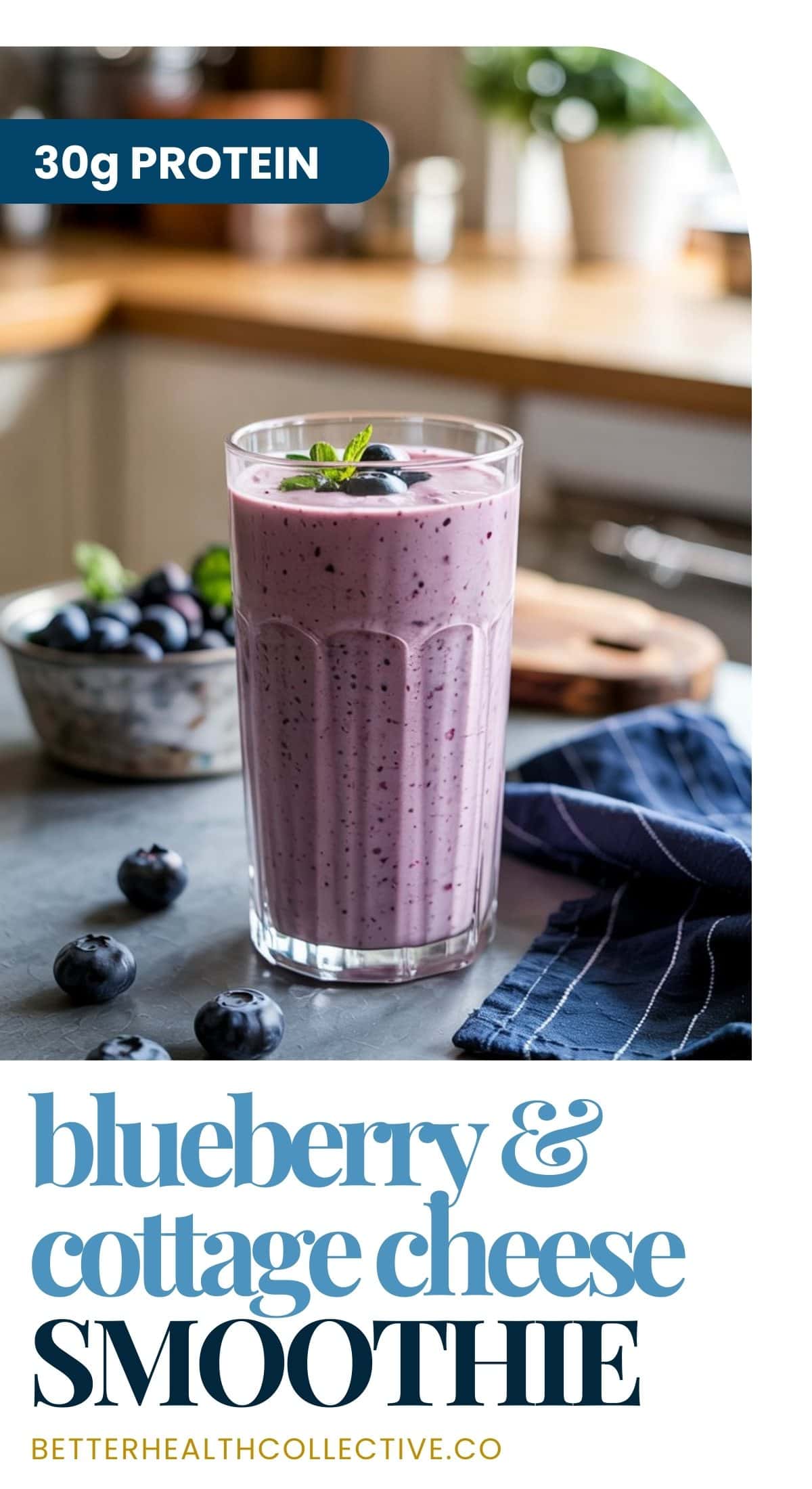 A tall glass of blueberry vanilla cottage cheese smoothie sits on a kitchen counter, garnished with mint, fresh blueberries, and a bowl of berries nearby. Text reads 30g protein and high-protein blueberry & cottage cheese smoothie.