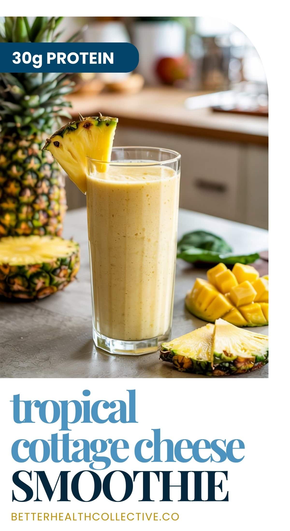 A glass of tropical cottage cheese smoothie garnished with pineapple sits on a kitchen counter, surrounded by fresh pineapple and mango pieces. Text reads 30g PROTEIN and tropical cottage cheese smoothie.