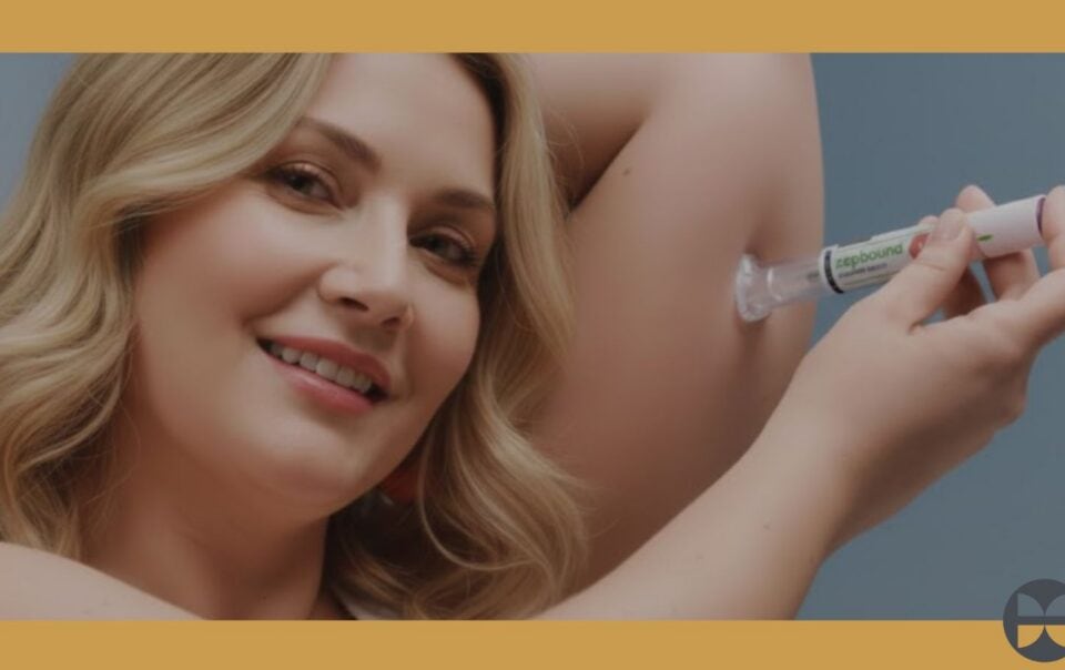 A smiling woman with wavy blonde hair applies a cream or gel from a tube to her underarm, showing where to take care for best results. The blue background has orange borders and a small circular logo in the lower right corner.