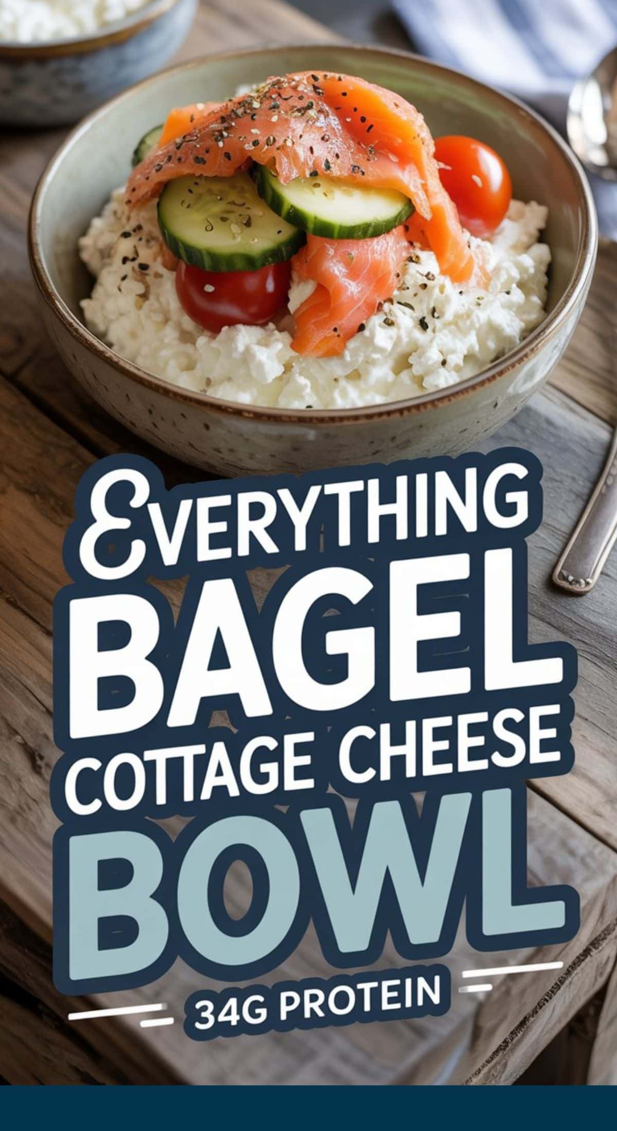 A bowl of cottage cheese topped with smoked salmon, cucumber slices, cherry tomatoes, and everything bagel seasoning. Text overlay reads: Cottage Cheese Bagel Bowl, 34g Protein.